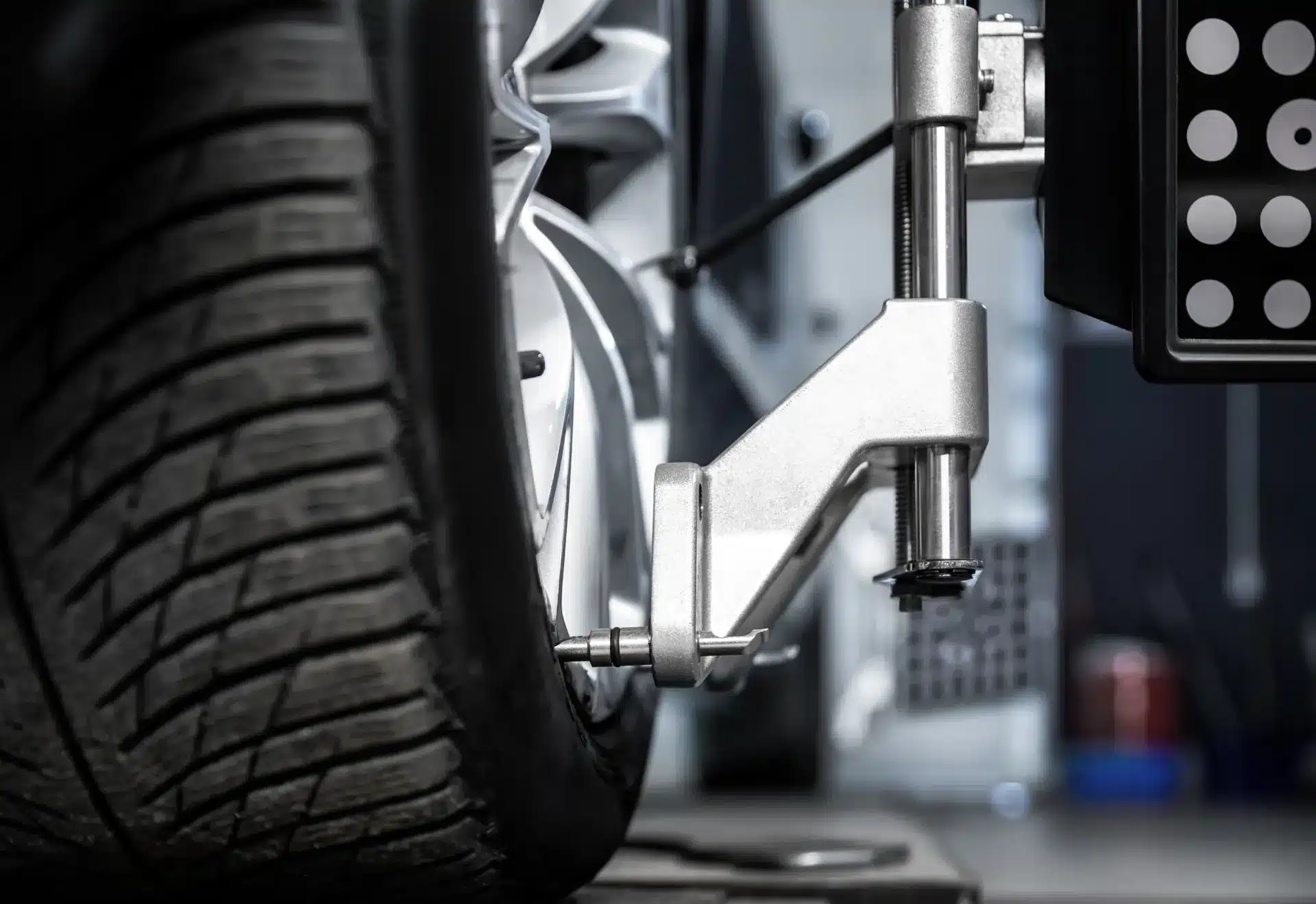 Close-up of a car wheel undergoing alignment at My Car Guy of Plant City in Plant City, FL, with a specialized tool attached to the tire and rim to measure and adjust wheel angles for proper alignment in a workshop setting.